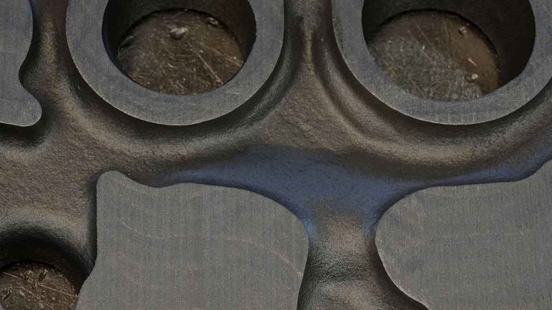 Precision in Metal Casting: A Detailed View Close-up view of a foundry-cast metal part with circular cavities and a textured surface, highlighting the precision and detail in metalworking.