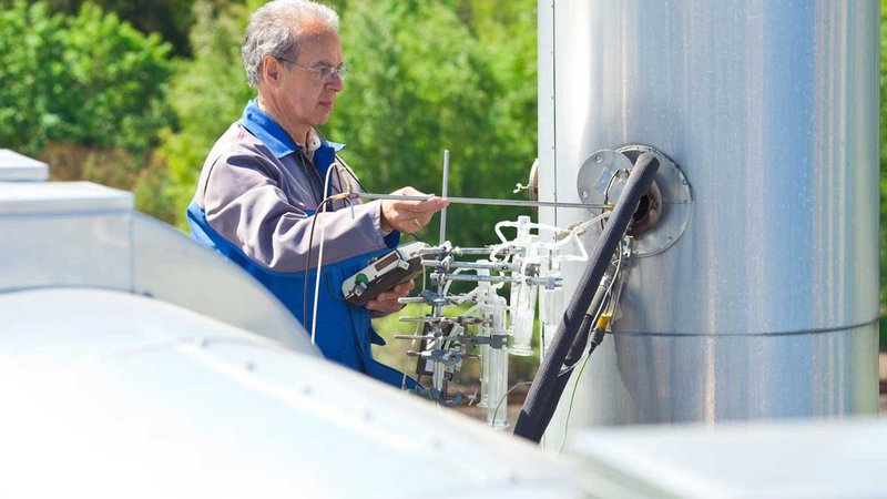 Worker measures atmosphere with a specific device A man measuring the atmosphere with a specific device. He wears a blue collar.